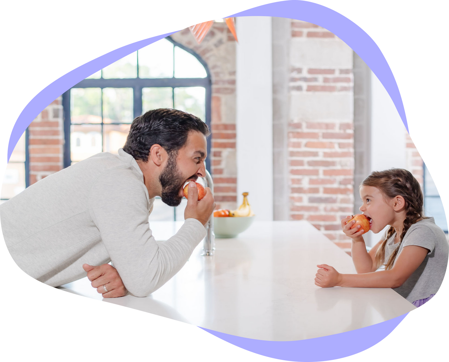 photo of a father and daugheter eating apples in their kitchen