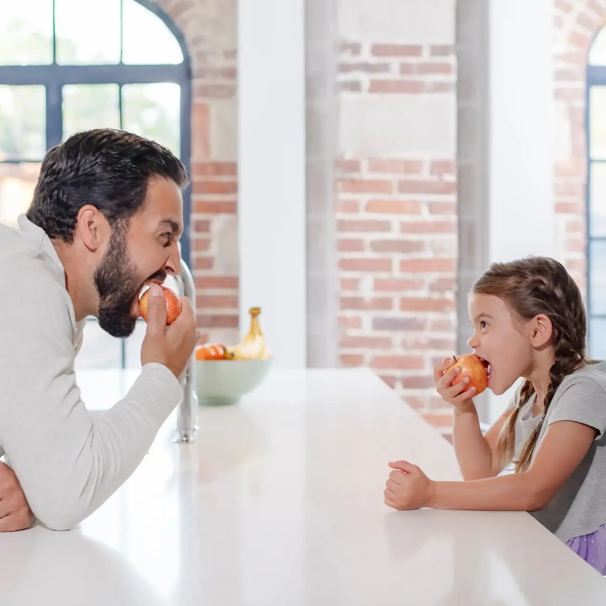 Father and daughter eating an apple in there kitchen